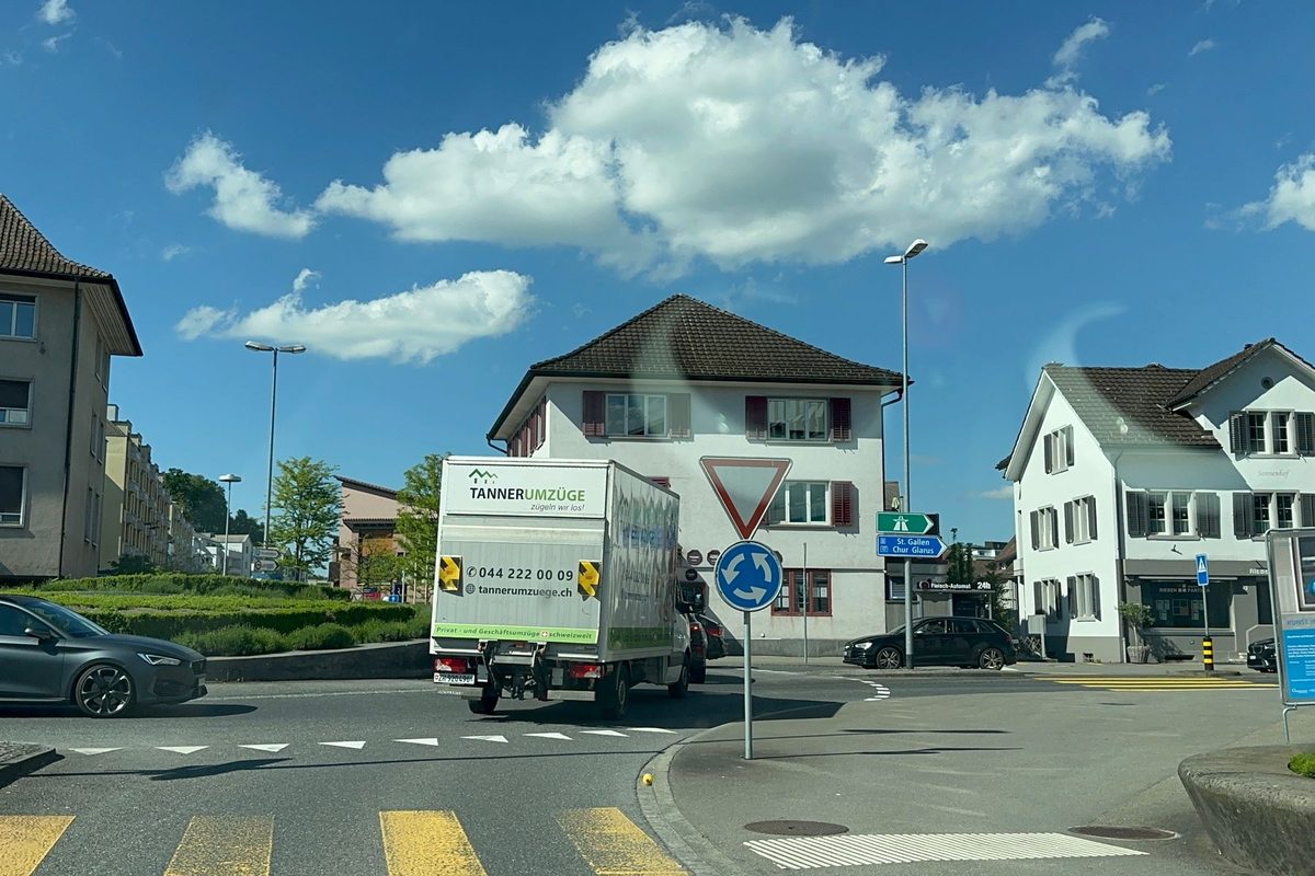 Umzugsfirma Zollikon: Umzugswagen von Tanner Umzüge an einer Kreuzung zwischen Wohnhäusern