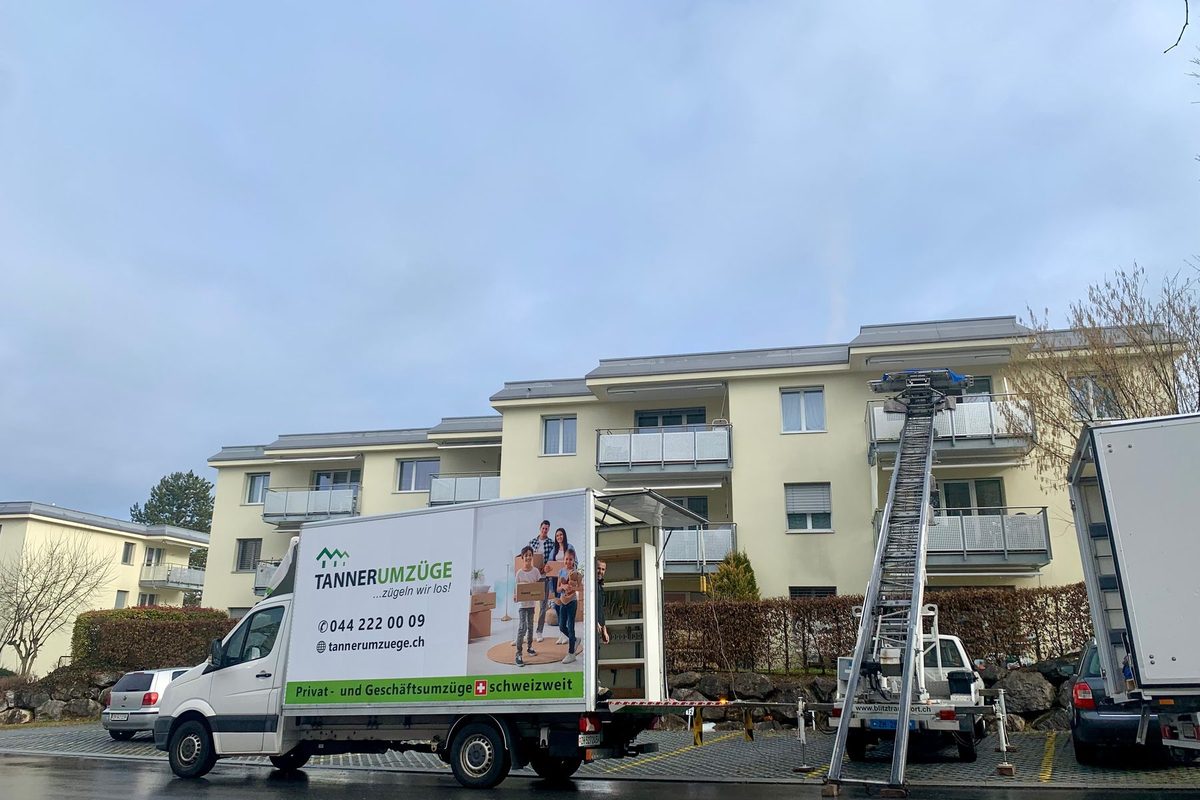 Sofa und Kisten stehen auf der Plattform des Möbellifts vor einem Balkon