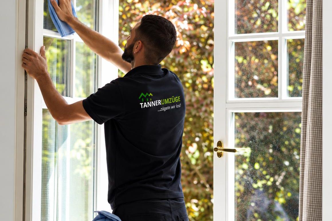 Ein Mitarbeiter von Tanner Umzüge reinigt ein geöffnetes Holzfenster
