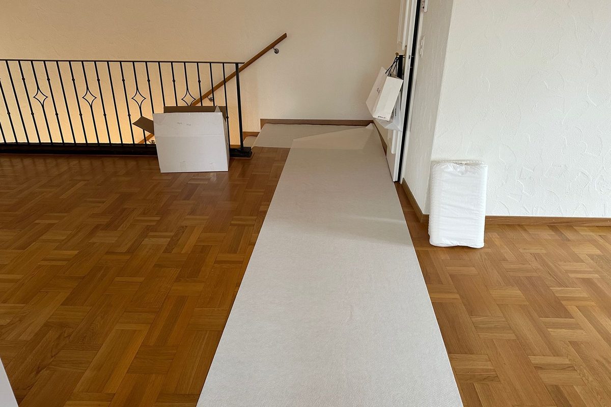 Mit Schutzvlies ausgelegter Parkettboden in einer leeren Wohnung