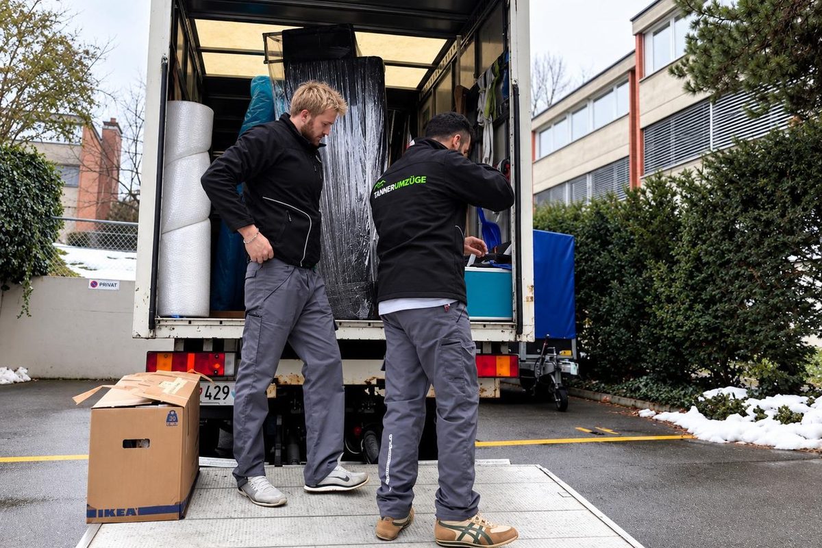 Zwei Mitarbeiter von Tanner Umzüge beladen den Umzugswagen an einem Wintertag