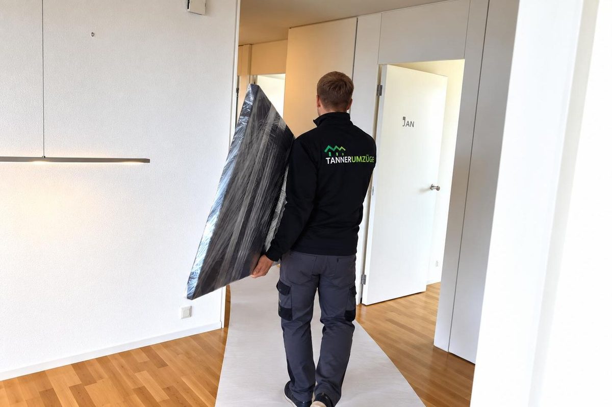 Ein Mitarbeiter von Tanner Umzüge trägt einen zusammengerollten Teppich durch eine leere Wohnung